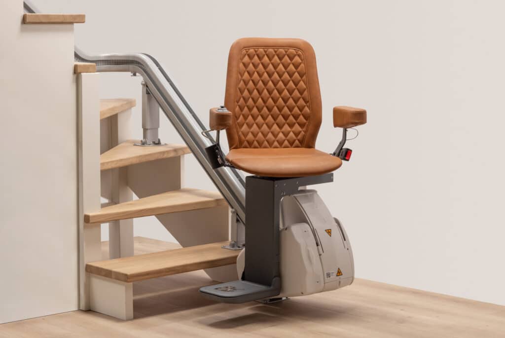 Monte-escalier Design & Confort : Siège Cuir pour Votre Maison Fauteuil monte-escalier marron élégant avec siège en cuir matelassé, installé sur un escalier en bois clair. Rail gris discret.