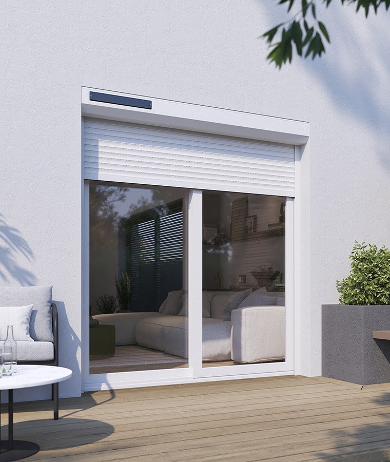 Volet Roulant Solaire pour Baie Vitrée | Confort Durable Volet roulant solaire blanc installé sur une baie vitrée donnant sur une terrasse moderne en bois.